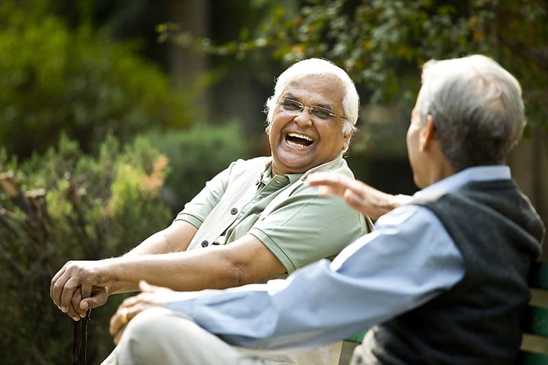 Two elderly gentlemen laughing and enjoying themselves outside